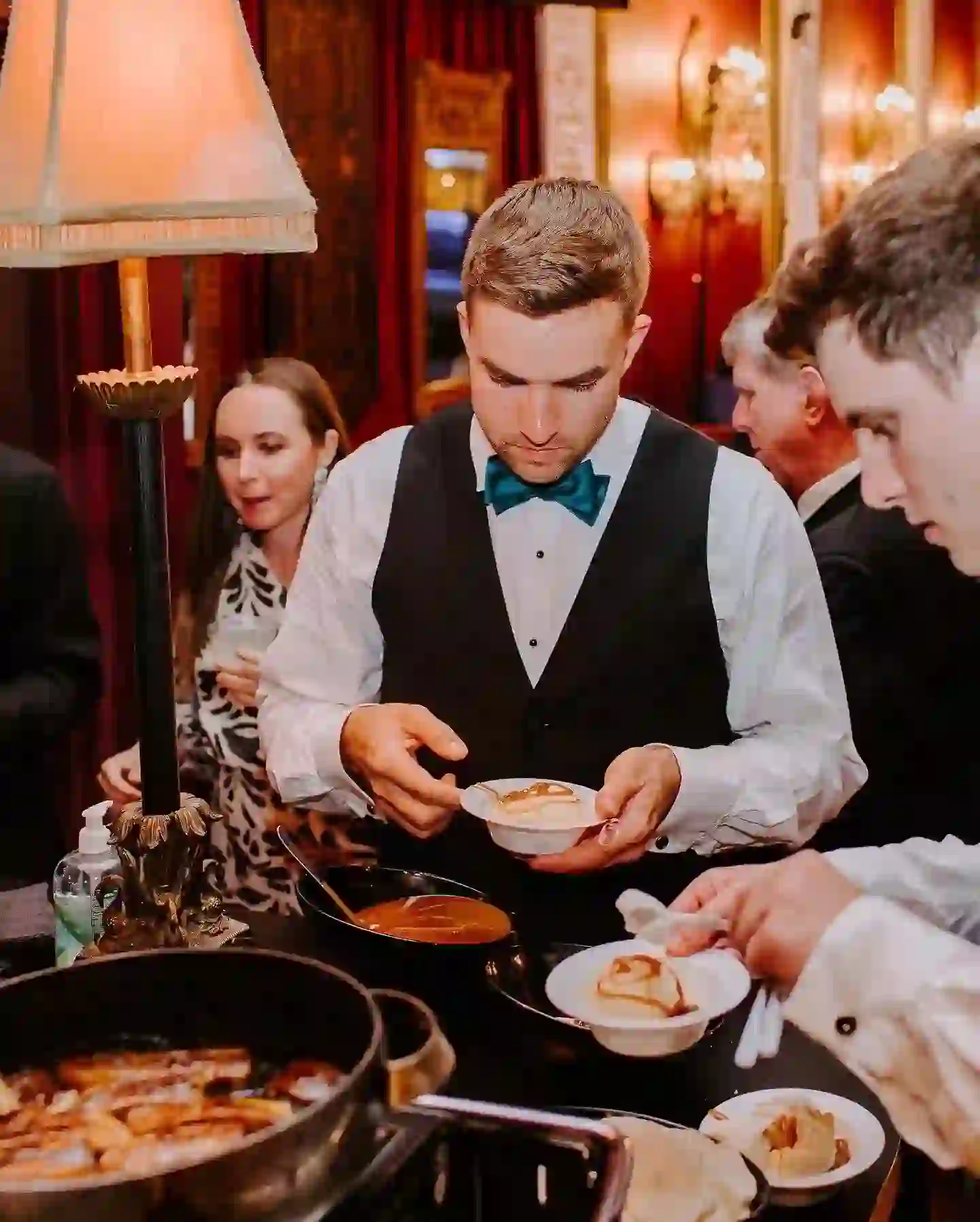 People serving food at formal event.