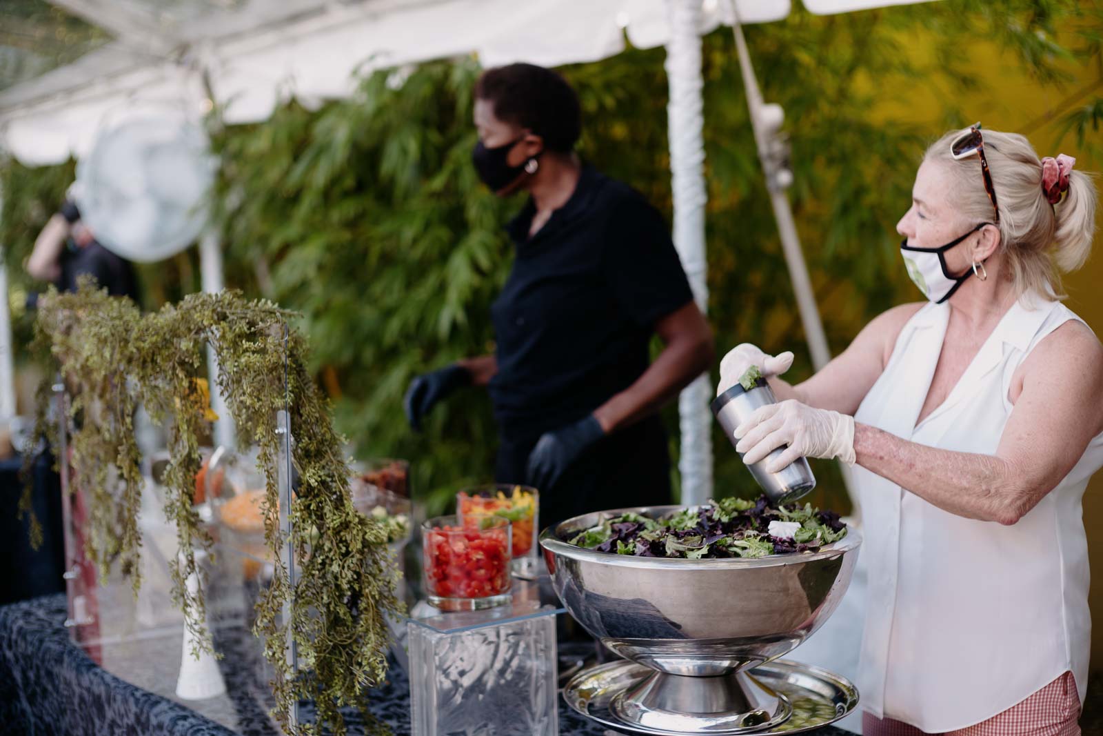 Woman seasoning salad at outdoor event.