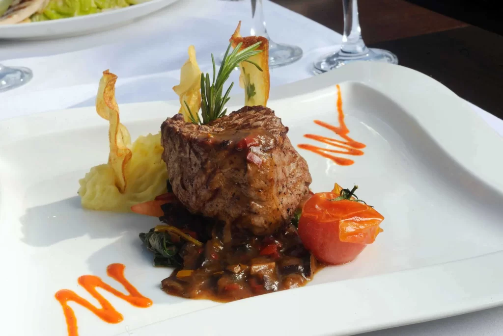 Gourmet steak dish with artistic presentation on white plate.