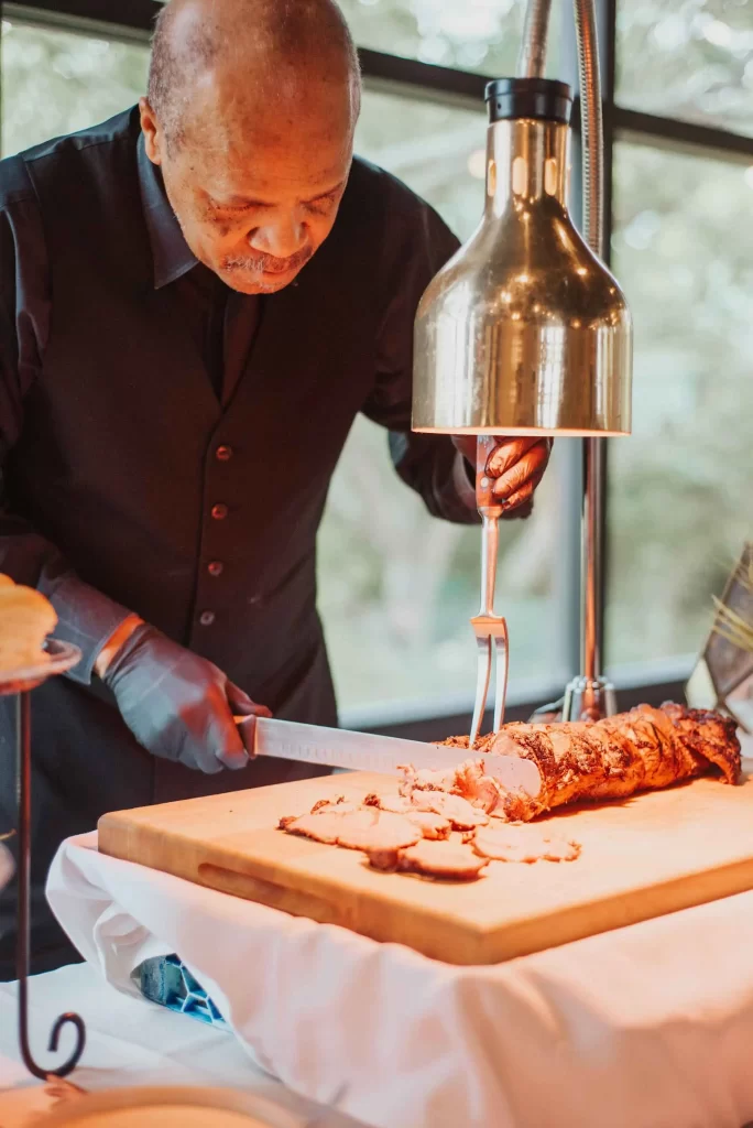 Chef carving roasted meat at buffet station.