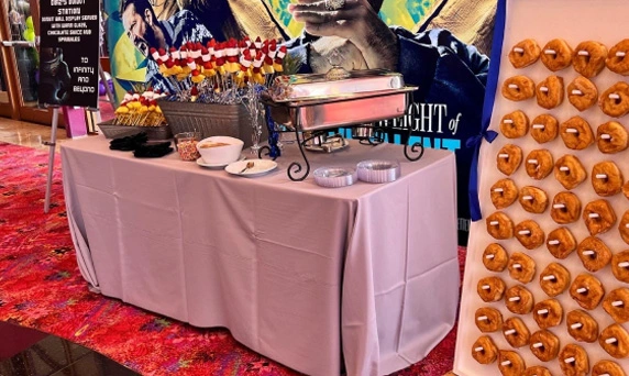 Catering table with pretzels and movie poster at event.