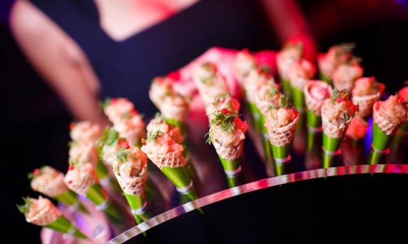 Catering shrimp appetizers in cones at an event.
