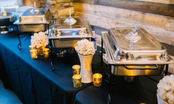 Elegant catering buffet with warmers and floral decorations.