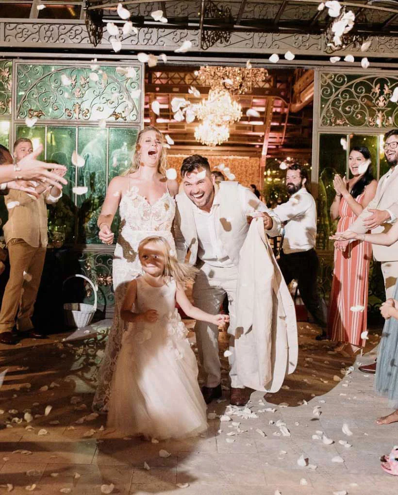 Joyful wedding exit with flower petals and happy couple.