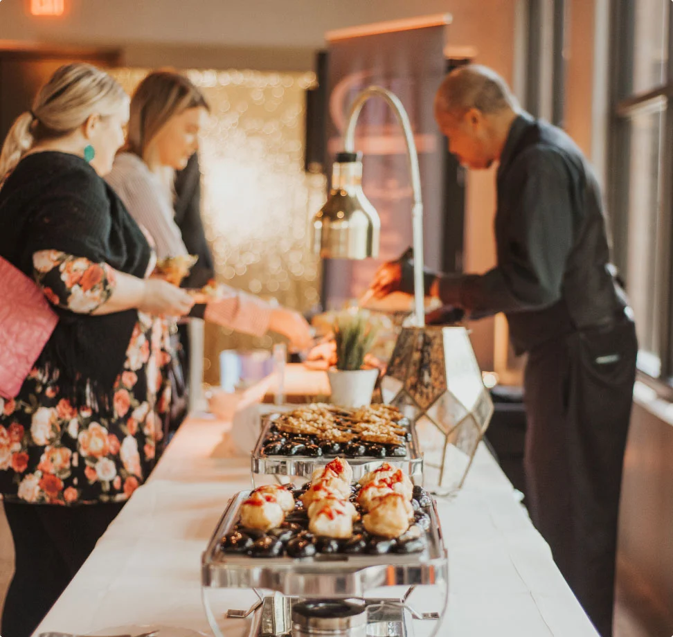 People at buffet with desserts in event setting.