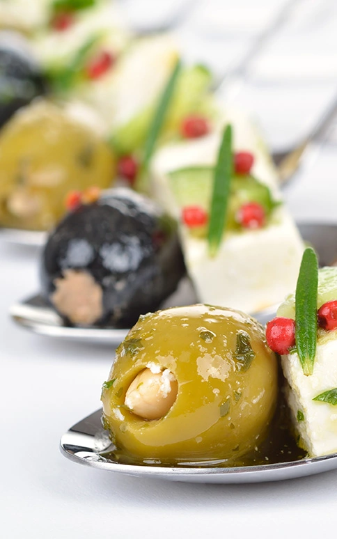 Assorted stuffed olives on small spoons, appetizers.
