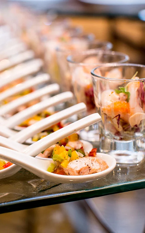 Assorted gourmet appetizers on spoons at event.