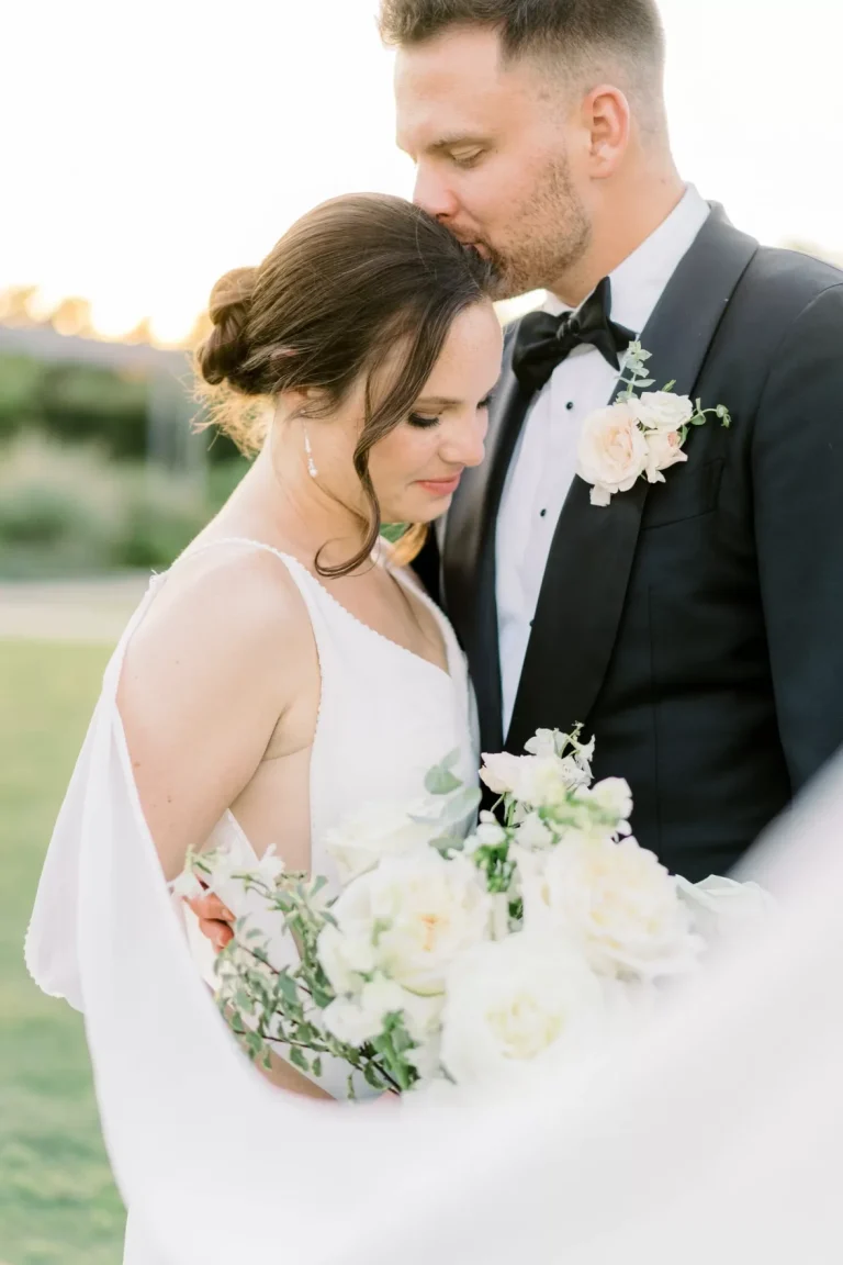 Bride and groom embrace with bouquet