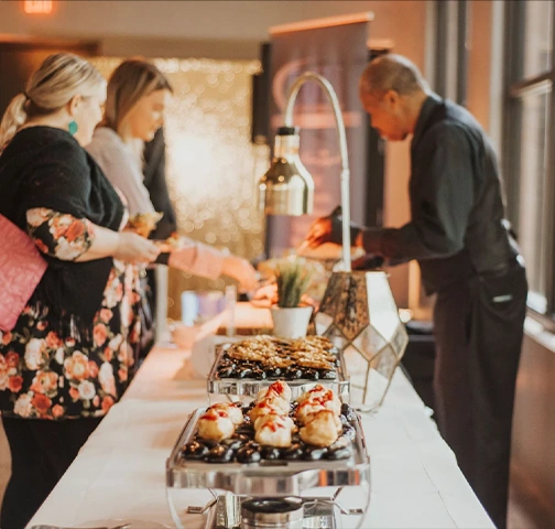 Guests serving themselves at buffet event table.
