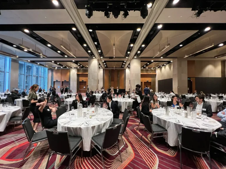 Banquet hall with people seated at round tables.