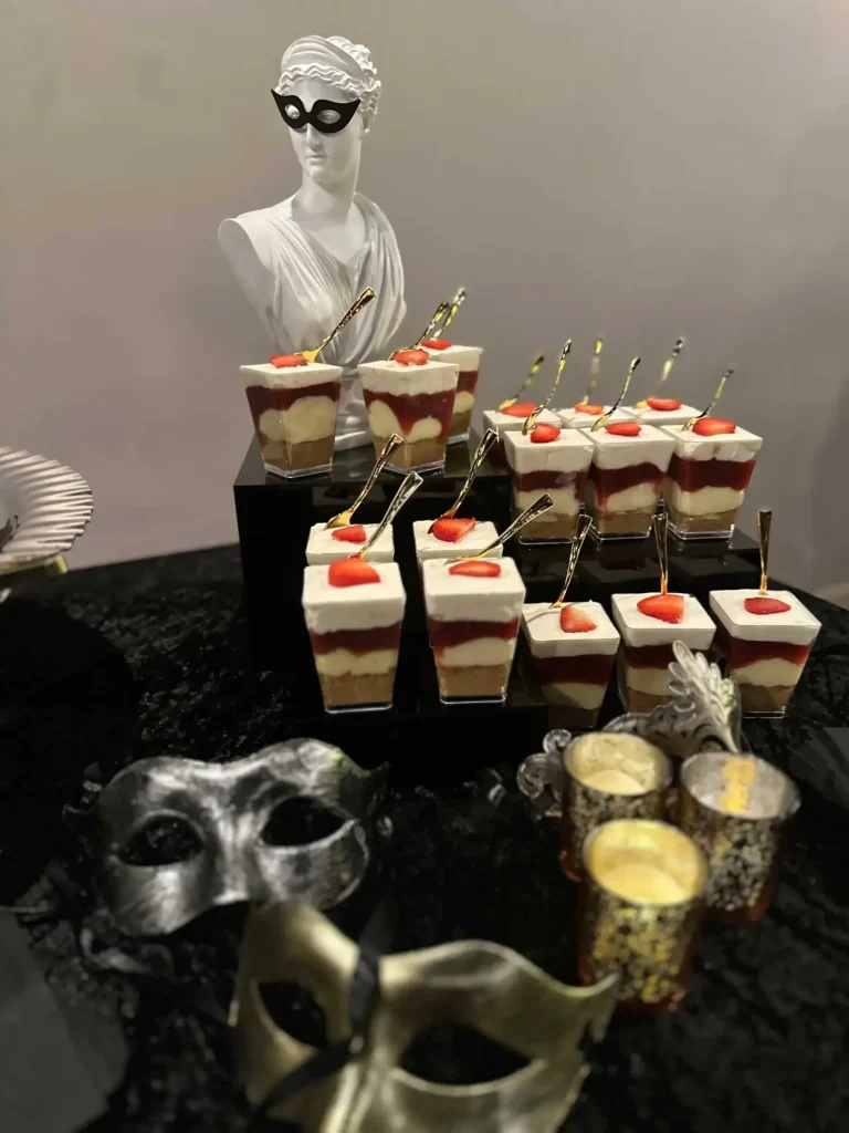 Masquerade-themed dessert display with masks and candles.