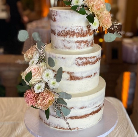 Three-tier naked cake with floral decoration.
